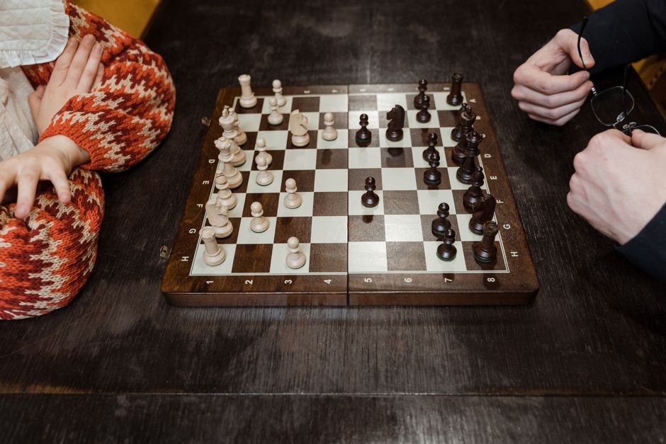 Two people playing chess across a wooden board