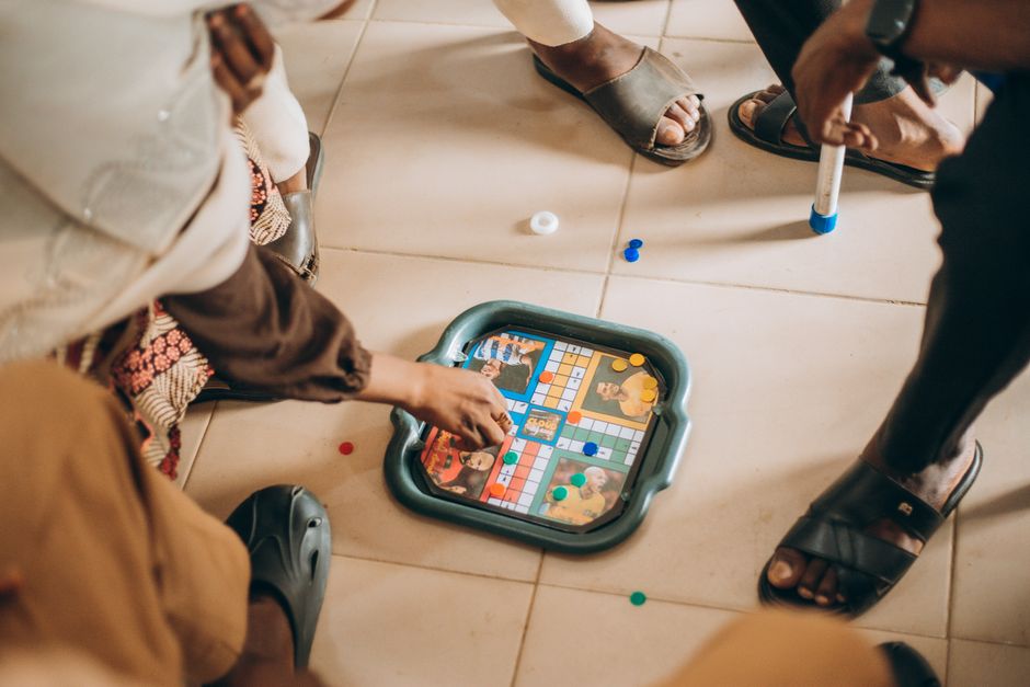 A mixed-experience group of players around a board game